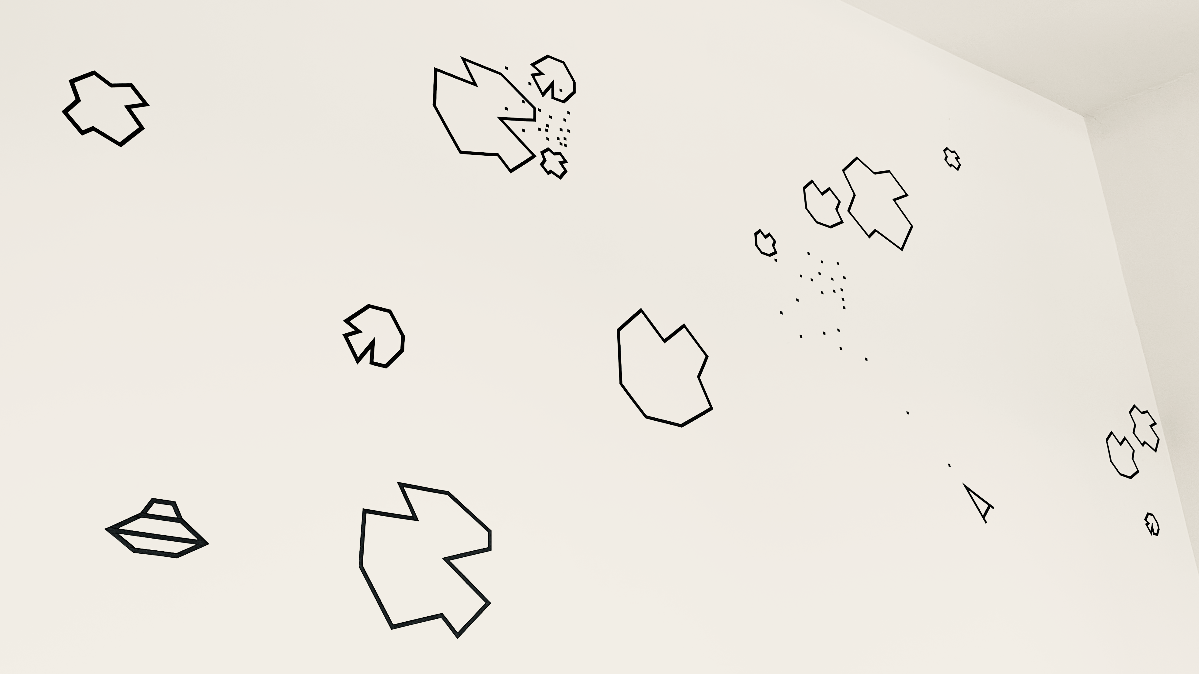 Black-outlined asteroid shapes and scattered dots drawn across the pale wall and ceiling of a studio.